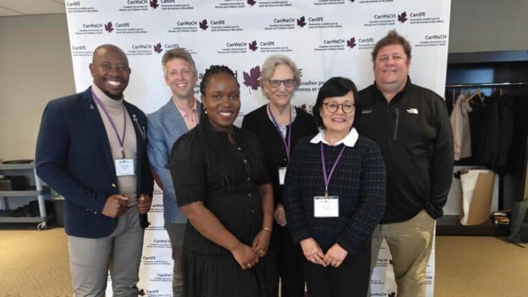 Group of conference attendees standing in front of a CanWaCH backdrop with event signage.