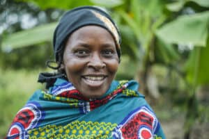 Smiling Kenyan woman in traditional attire in a water project area.