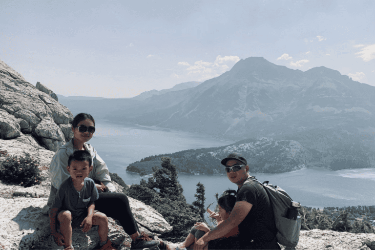 Hikers enjoying a mountain lake view with mountains in the background.