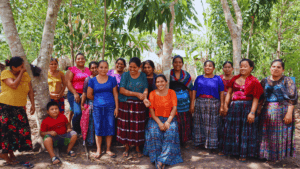 Group of women and children in traditional Guatemalan clothing outdoors.
