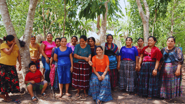 Group of women and children in traditional Guatemalan clothing outdoors.