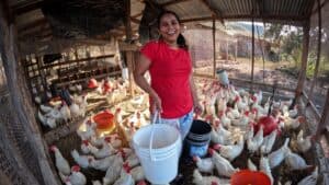 Happy woman with chickens in a rustic farm setting.