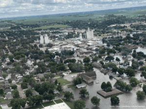 Aerial view of a town with flooded streets and water surrounding homes, buildings, and roads.