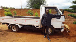 Man standing next to a white truck in a rural Mozambique setting.