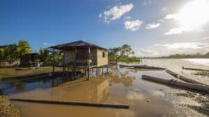 Flooded house on stilts in Nicaragua with muddy water and boats nearby.