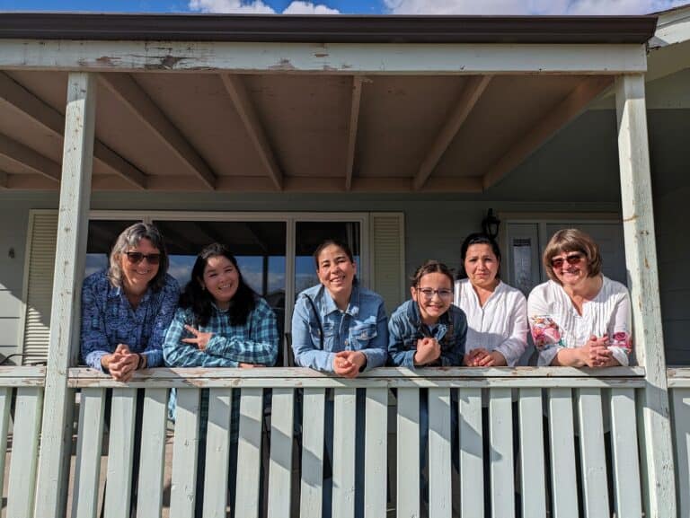 Group of diverse women smiling on a balcony for refugee support in Canada.