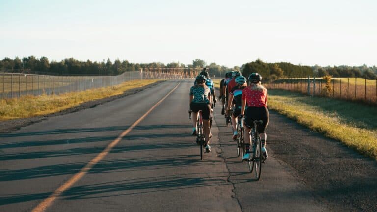 Cyclists riding together on a rural open road during daytime.