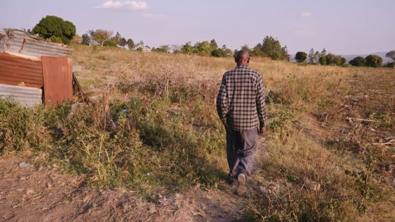 Father walking through rural field in Tanzania, symbolizing dedication and hope.