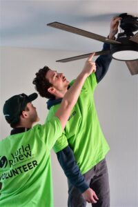 Volunteers installing a ceiling fan during a community service project.