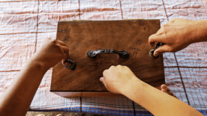 People playing a traditional game with small stones and a wooden board.
