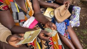 Women exchanging money and documents in a community setting in Zambia.