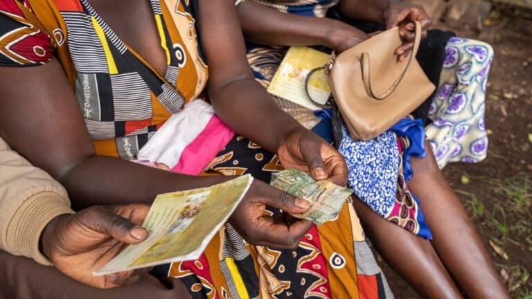 Women exchanging money and documents in a community setting in Zambia.