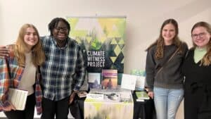 People standing beside a Climate Witness Project display table with educational resources.