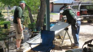 Volunteers work outdoors cutting and preparing a door during a home repair project.