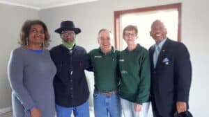 Five people standing together inside a newly repaired home following disaster recovery work.