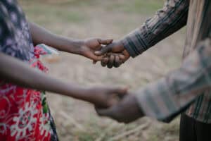 Two people holding hands outdoors in a gesture of support and connection.