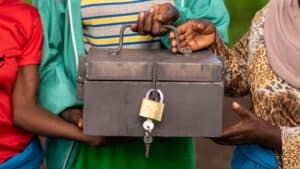 Community members hold a locked savings box used by a village savings and loan association to build a Mozambique business.
