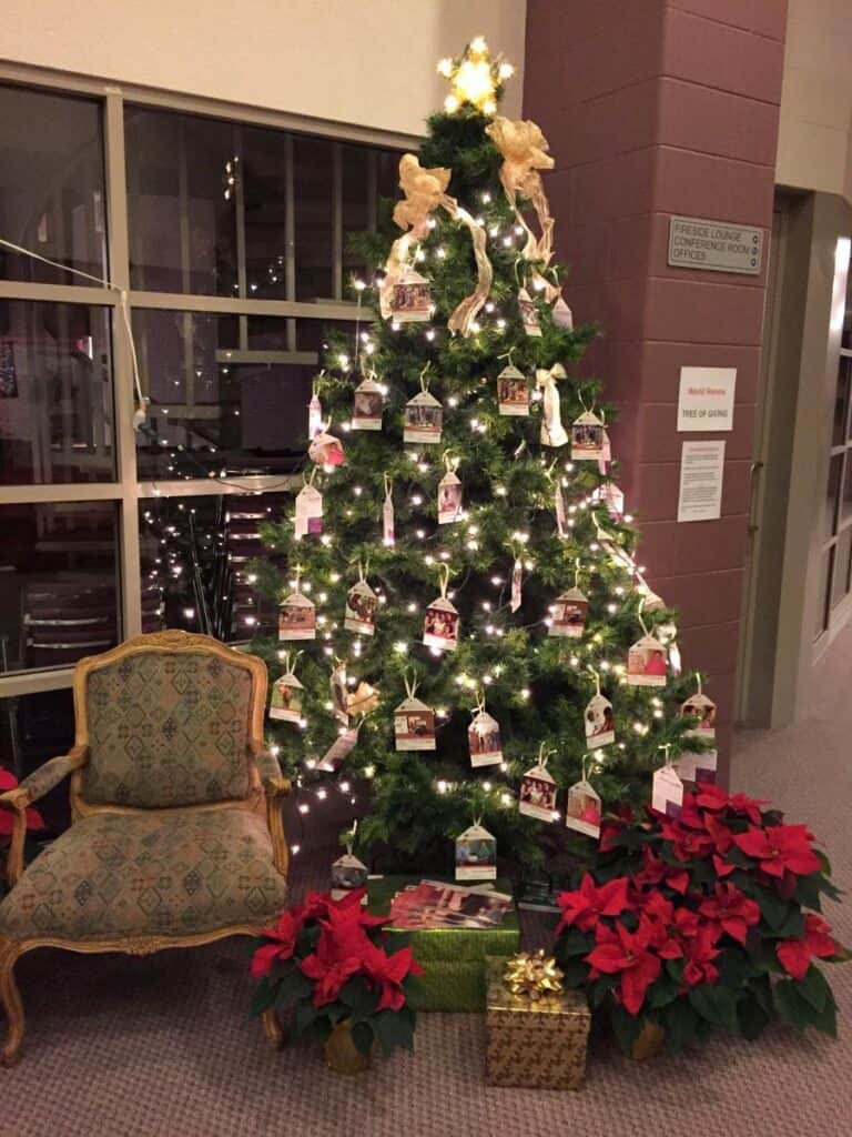 Decorated Christmas tree with donation tags displayed inside a church building.
