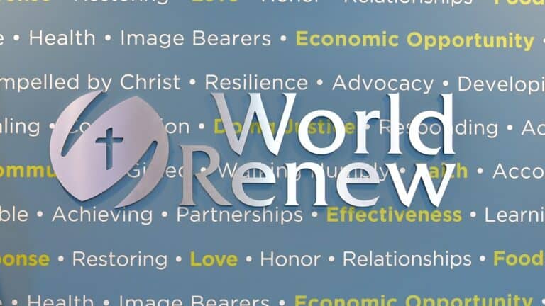 World Renew logo displayed on a blue wall with organizational values and mission-related words in the background.