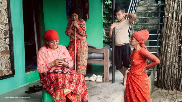 People gather outside a home in Nepal after severe flooding affected local communities.