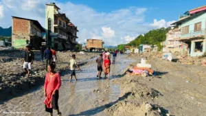 People walk along a mud-covered street after severe flooding damaged homes and infrastructure.