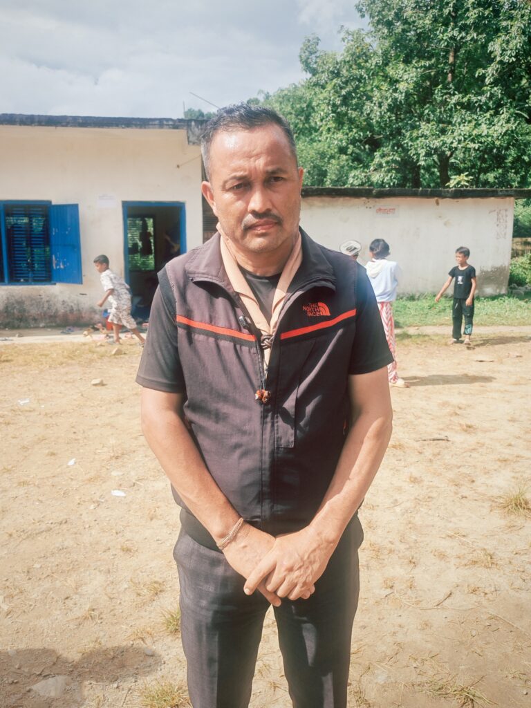 Shyam Pudasaini stands near a temporary shelter supporting families affected by flooding in Nepal.